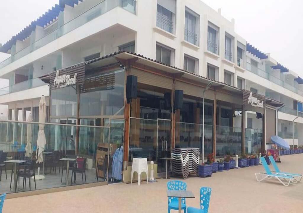 A beachfront restaurant with outdoor seating and a covered patio area.