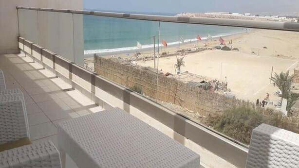Un balcon avec vue sur une plage et l’océan.