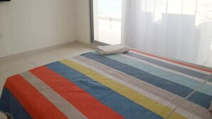 Une pièce avec un tapis à rayures, une serviette blanche sur le sol et une grande fenêtre donnant sur la plage.