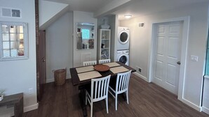 A compact kitchen with a dining area, a washing machine, and a door.