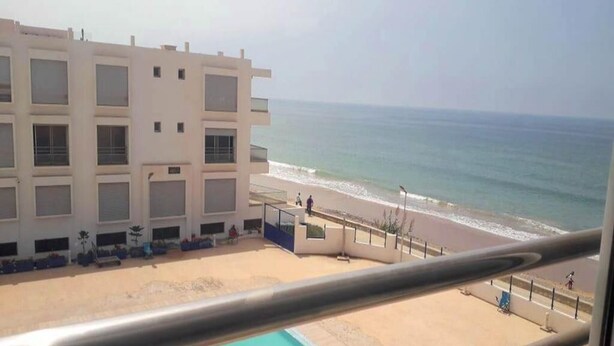 Een hotel met zwembad, uitzicht op het strand en een gebouw met meerdere balkons.