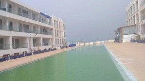 A swimming pool adjacent to a multi-story hotel with balconies.