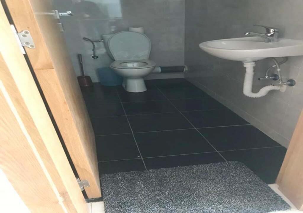 Et badeværelse med toilet, vask og bruseområde.