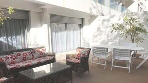 Eine Terrasse im Freien mit Korbmöbeln, darunter eine Sitzecke mit Sofa und Stühlen sowie ein kleiner Tisch.
