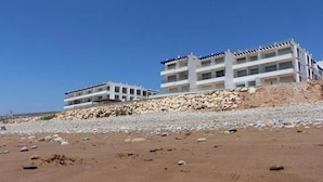 Un hotel frente al mar con varios pisos, una costa rocosa y cielos despejados.