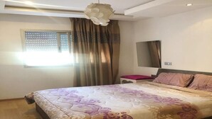 Un dormitorio con una cama, una mesita de noche, un espejo y una ventana con cortinas.