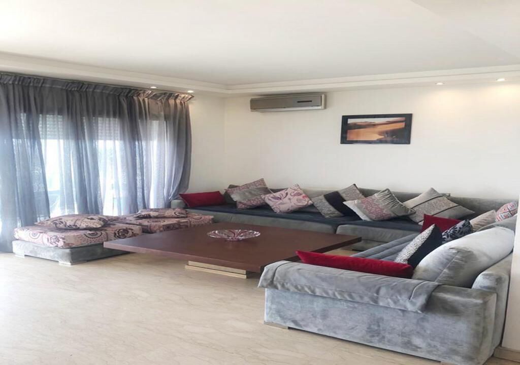 A modern living room with a sectional sofa, a coffee table, and a large window with curtains.
