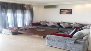 Una sala de estar moderna con un sofá seccional, una mesa de centro y un ventanal con cortinas.