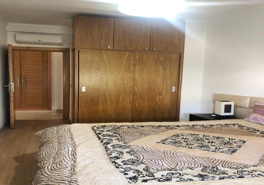 A bedroom with a bed, a wardrobe, and a nightstand.