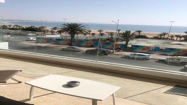Un balcón con vista a una playa y un estacionamiento.