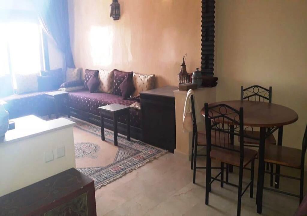 A living room with a sofa, a dining table with chairs, a patterned rug, and a decorative lantern.