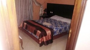 Ein Schlafzimmer mit Bett, Nachttisch und Vorhang.