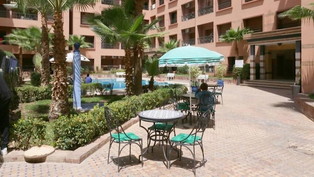 Ein Innenhof mit Pool, Palmen und Sitzgelegenheiten im Freien.