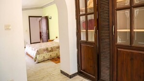Ein Schlafzimmer mit Bett, Kleiderschrank und einer rundbogenförmigen Tür zu einem anderen Raum.