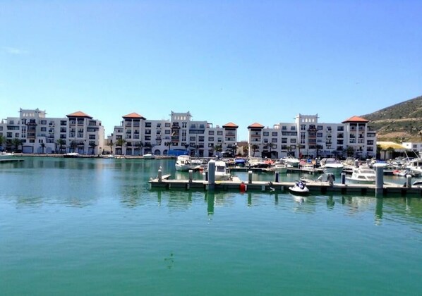 A marina with several white buildings with red roofs, docked boats, and a clear blue sky. - Marina Agadir Residence 4903 (Agadir)