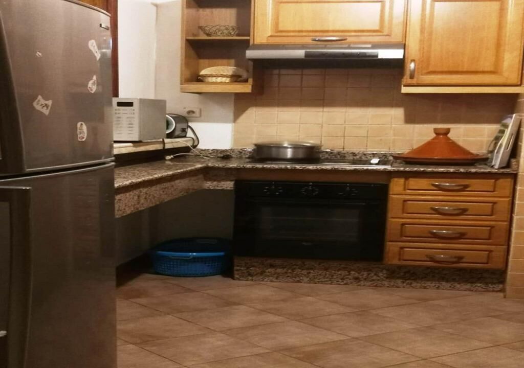 Una cocina con refrigerador, microondas, estufa, horno y alacenas de madera.