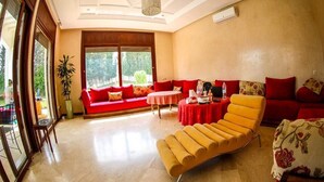 A spacious living room with a red sofa, yellow armchair, and a dining table. - Sublime Villa with swimming pool in Illigh Agadir 4906 (Agadir)