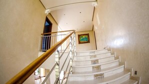 A curved staircase with white steps and a wooden handrail, leading to a landing with a framed picture. - Sublime Villa with swimming pool in Illigh Agadir 4906 (Agadir)