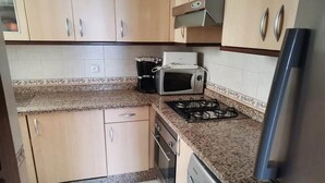 Una cucina con mobili in legno, un forno a microonde, un piano cottura a gas e una lavatrice.