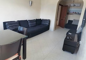 A living room with a sofa, a small table, and a TV.