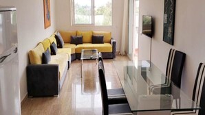 Uma sala de estar moderna com um sofá, uma mesa de jantar de vidro e uma televisão.
