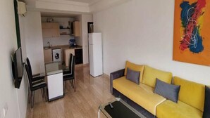 Um espaço de estar compacto com área de refeições, cozinha compacta e sofá.