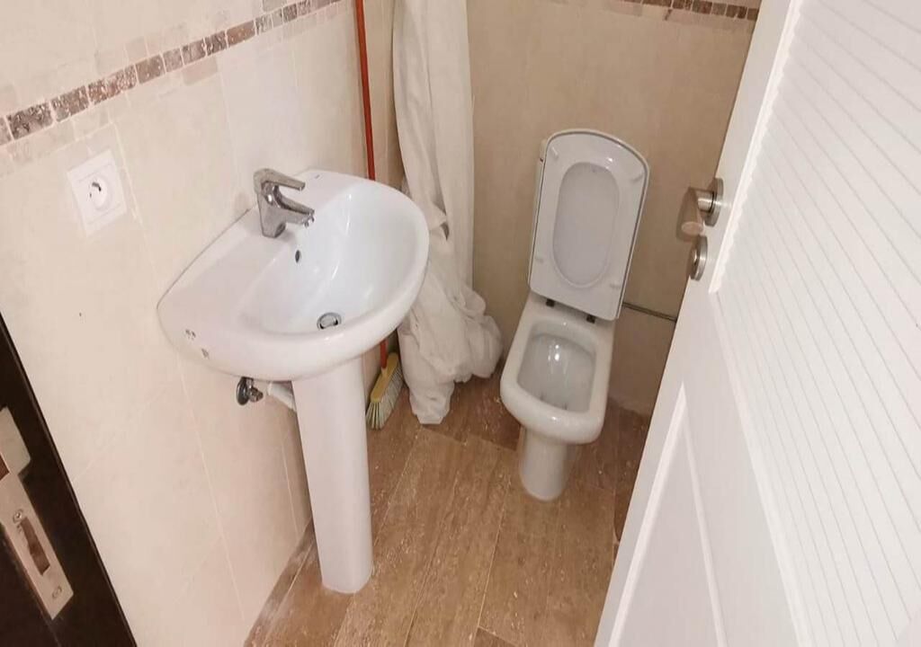 Une petite salle de bain avec un lavabo blanc, des toilettes et un rideau de douche.