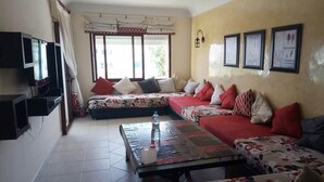 A living room with a sofa set, a coffee table, a television, and framed pictures on the wall. - Residence Kabila Vista 4941 (Mdiq)