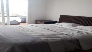 Een slaapkamer met een bed, een nachtkastje en een schuifdeur naar een buitenruimte.