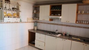 Cozinha com armários brancos, fogão a gás e painel de azulejos.