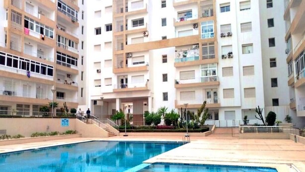 Une piscine entourée d’immeubles résidentiels à plusieurs étages, dotés de balcons.