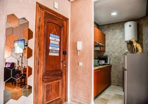 A wooden door with a sign, a kitchen with a microwave, and a water dispenser. - Residence Caprice Palace 4989 (Marrakech)