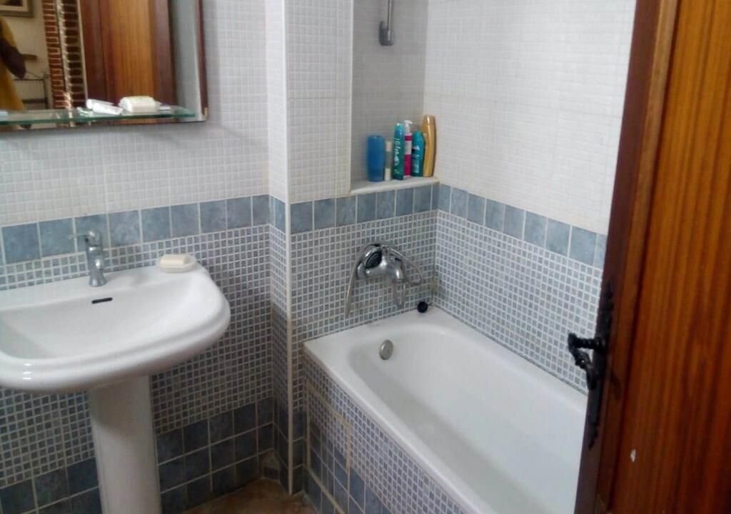 Une salle de bain avec un lavabo blanc, une baignoire et un miroir au-dessus du lavabo.