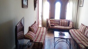 Una sala de estar con sofás a rayas, una mesa de centro y un televisor.