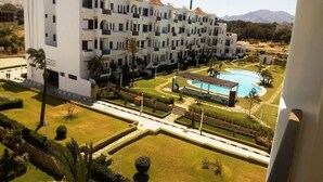 Un hotel de varios pisos con piscina y jardines cuidados.