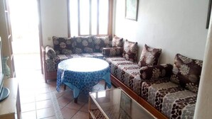 Un salón con un conjunto de sofás, una mesa de centro redonda y una mesa con superficie de vidrio.