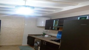 A compact kitchen with a washing machine, a refrigerator, and a microwave. - Residence Riviera Beach 5017 (Cabo Negro)