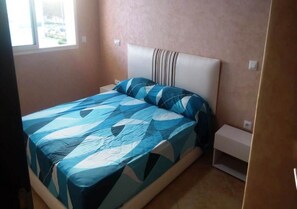 A bedroom with a bed, nightstands, and a window.