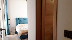 Een slaapkamer met een bed, een houten garderobe en een deur naar een andere kamer.