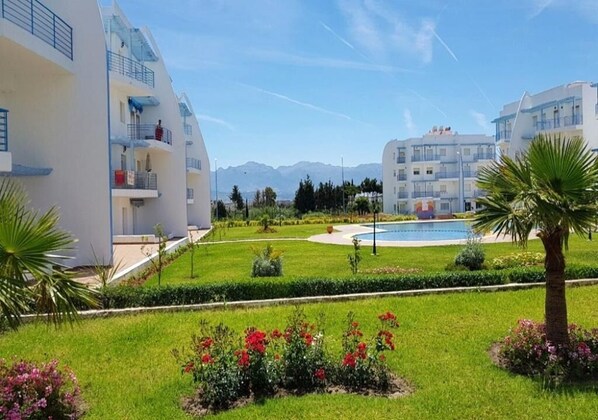 A modern hotel with a pool, manicured gardens, and mountain views.
