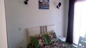 Une chambre à coucher avec un lit, un tableau au mur et une fenêtre avec des rideaux.