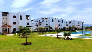 A white building with multiple balconies and a swimming pool.