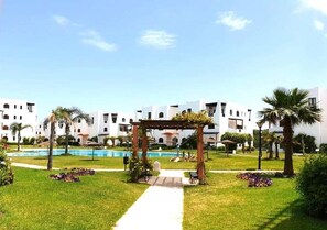 A hotel courtyard with a pool, a pergola, and palm trees. - Mangle 5035 Residence (Cabo Negro)