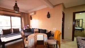 Ein gemütliches Wohnzimmer mit einer Couch, einem Esstisch mit Stühlen und einer kleinen Küchenzeile mit Spüle und Spiegel.