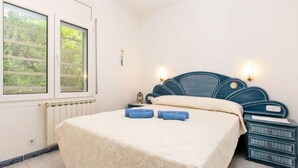 A bedroom with a bed, bedside tables, a window with a view of greenery, and a radiator. - Can Berta by Interhome (Pals)