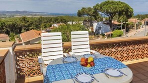 A terrace with a table set for dining, overlooking a scenic landscape with houses and trees. - Can Berta by Interhome (Pals)
