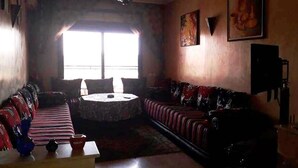 Un salon comprenant un ensemble de canapés, une table basse et une grande fenêtre laissant entrer la lumière naturelle.