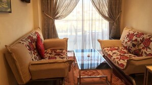 A living room with two sofas, a glass coffee table, and a television mounted on the wall. - Residence Appart Hotel Founty Beach 5135 (Agadir)