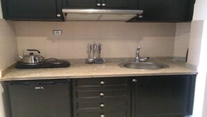 A compact kitchen with dark cabinets, a stainless steel sink, and a small refrigerator. - Residence Apart Hotel Founty Beach 5138 (Agadir)