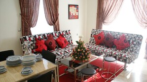 A living room with two patterned sofas, a coffee table, a dining table with plates, and a red rug. - Residence Appart Hotel Founty Beach 5142 (Agadir)